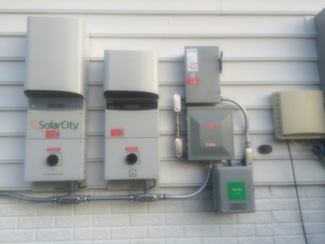Twin SolarCity inverters and disconnects on a house wall, July 2015