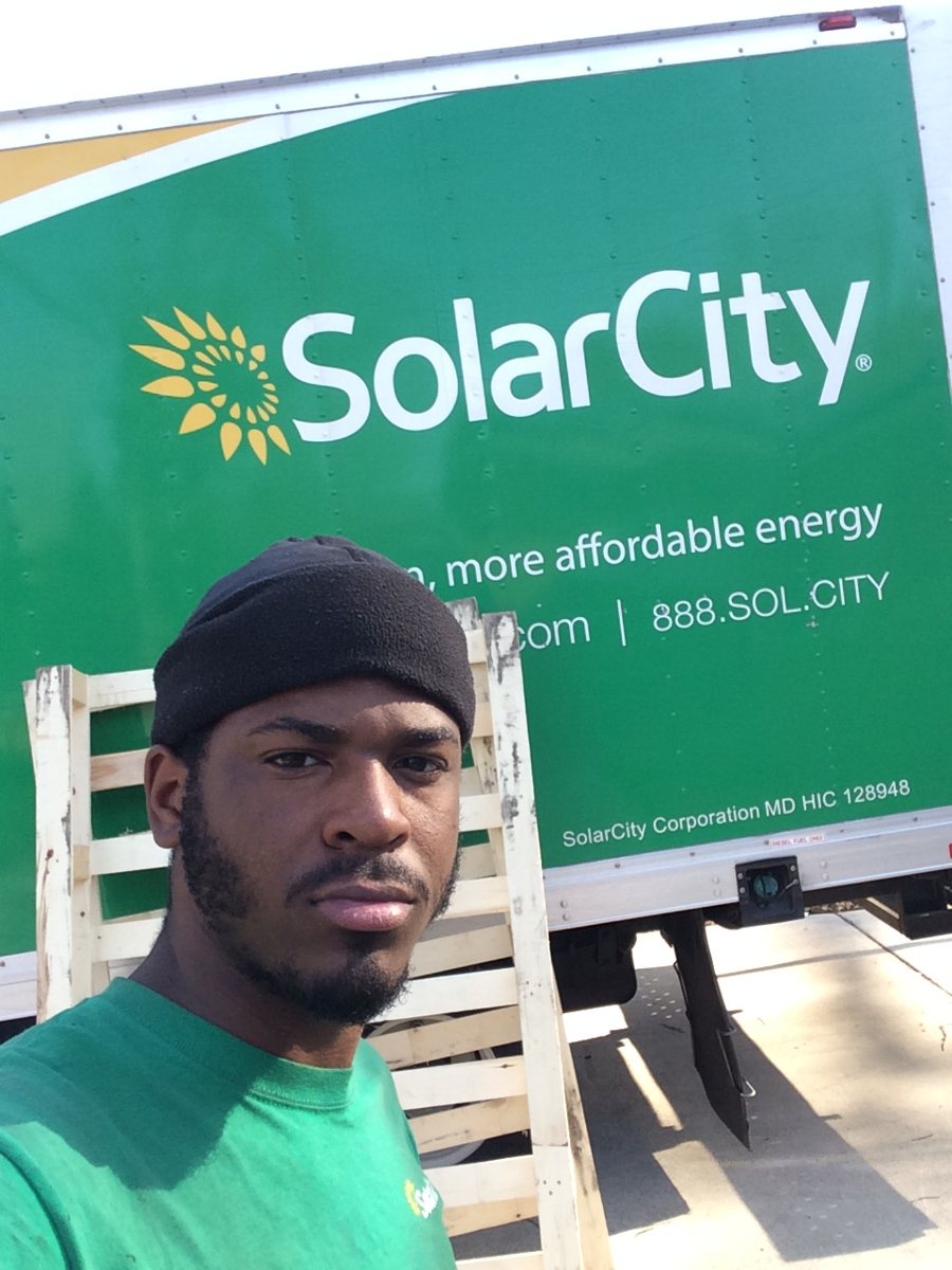 DaRoy Perkins in a SolarCity shirt in front of a SolarCity truck, 2015